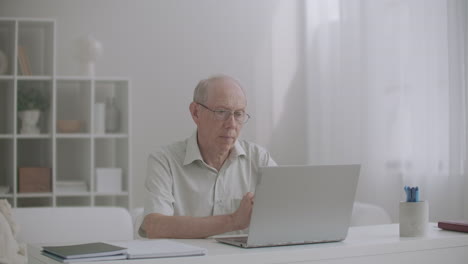 elderly-man-attorney-is-communicating-with-client-by-internet-consulting-by-web-camera-sitting-at-table-in-office